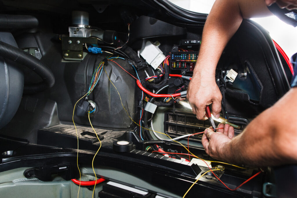 Mechanic cutting electrical wire in car